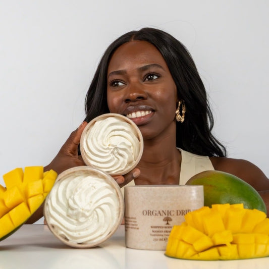 Woman holding Organic Drip Whipped Body Butter Mango with fresh mangoes.