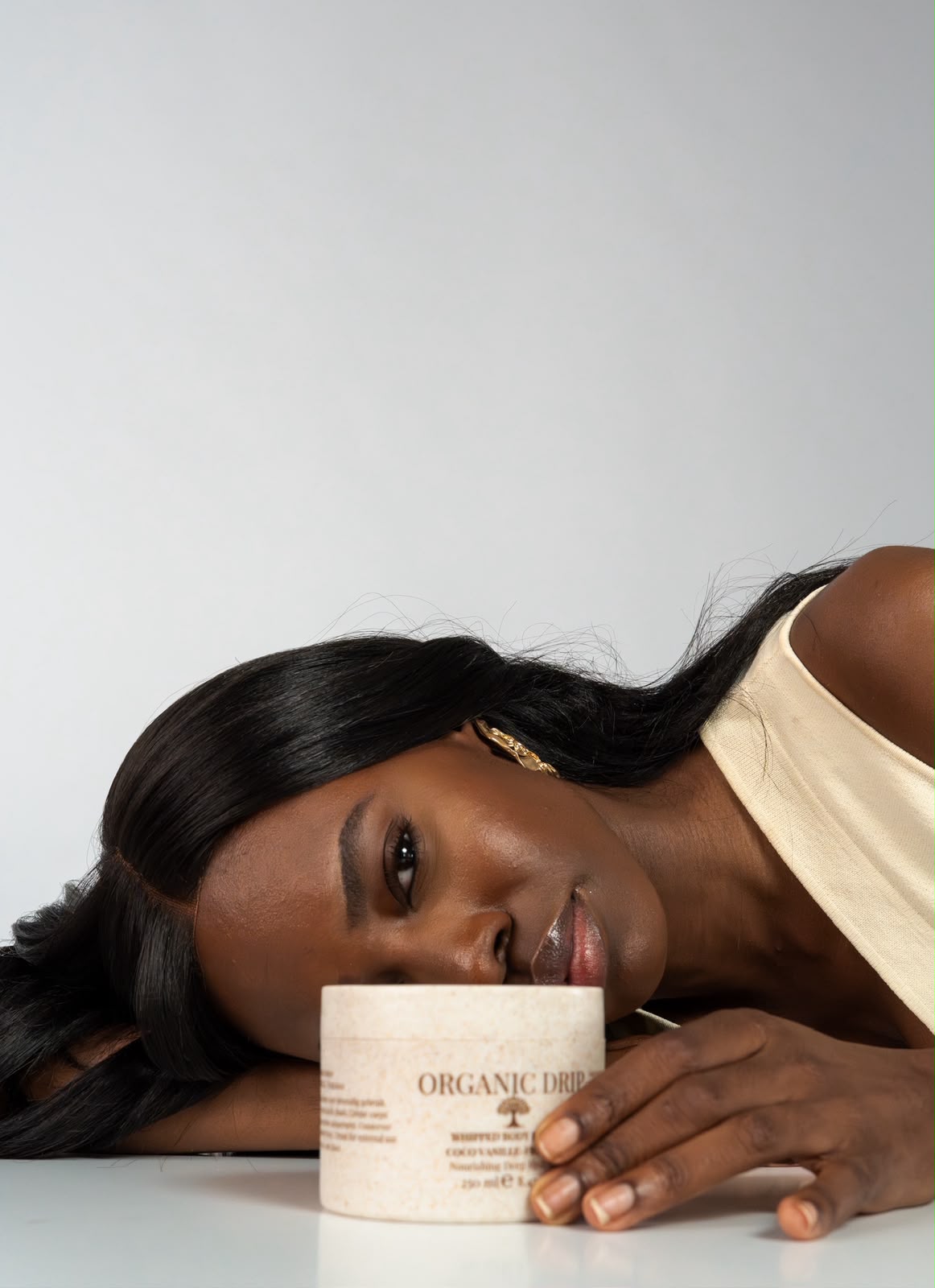 Model lying beside a jar of Organic Drip whipped body butter.